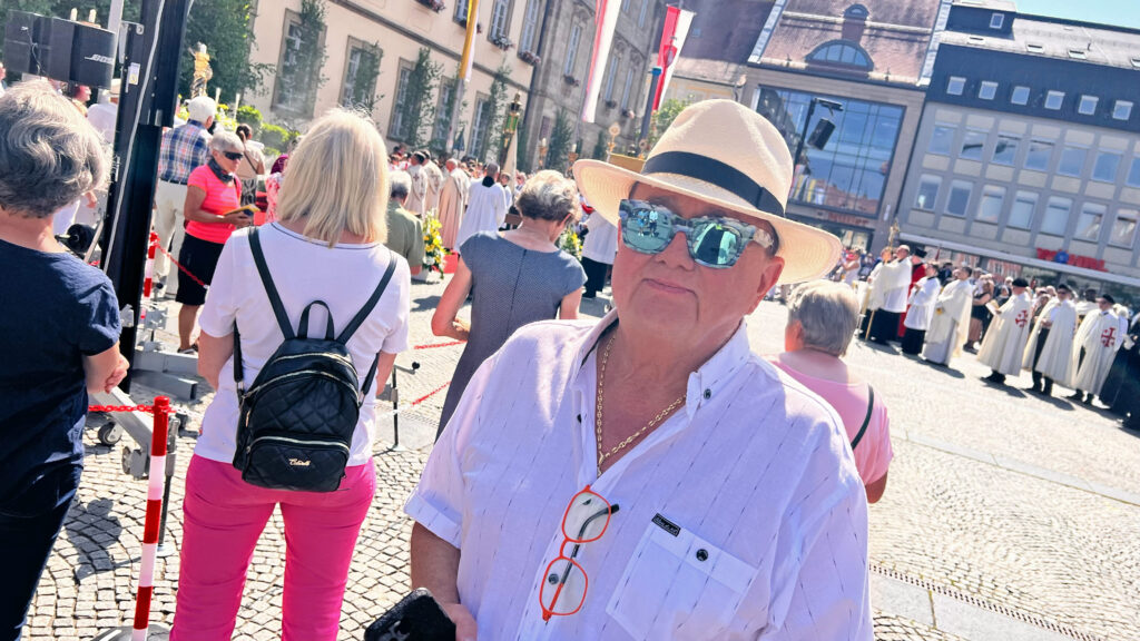 Michael Czerwenka auf dem Maxplatz während der Prozession. Im Hintergrund sprechen die Prozessionsteilnehmer Fürbitten. Foto: Sebastian Höfer