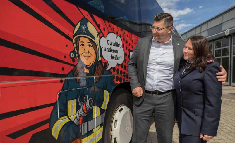 Vorbild trifft Comic: Feuerwehrfrau Sandra Neubert und Landrat Thomas Hennig an einem der beiden neuen Kampagnenbusse © Foto: Landratsamt Vogtlandkreis/David Rötzschke