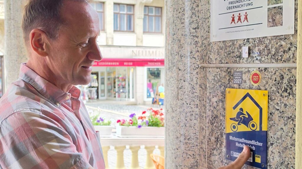 Anbringen des neuen Qualitätssiegels "Motorradfreundlicher Hotelbetrieb" im Eingangsbereich des Vier-Sterne-Hotels. Foto: Hotel Alexandra